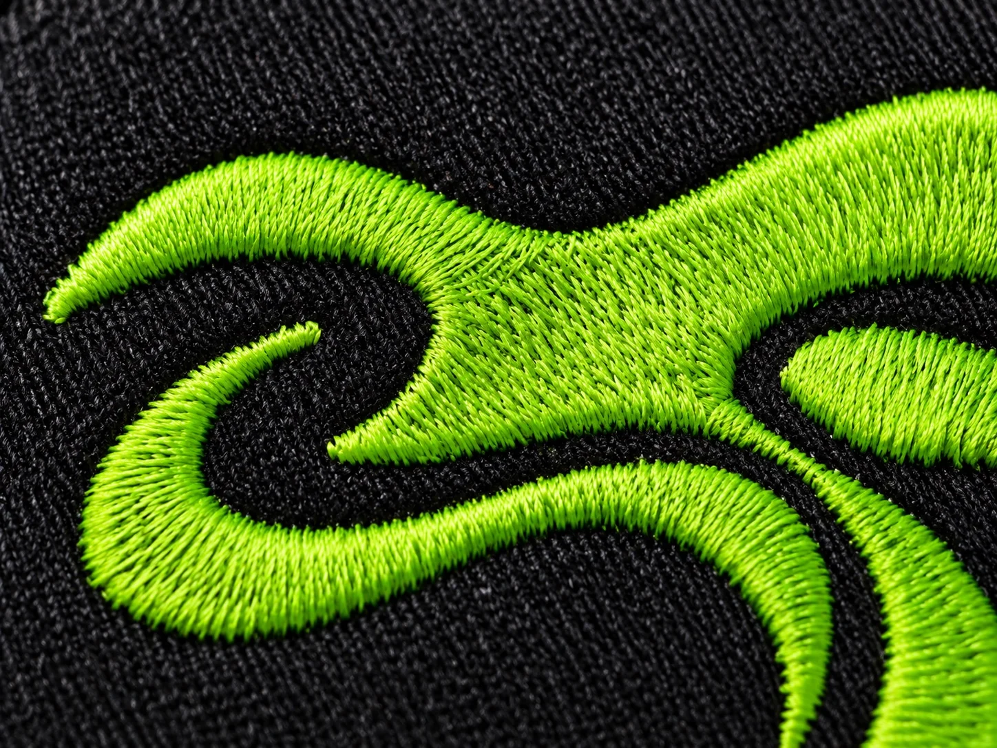 Lime embroidery threads on black cotton, in close detail